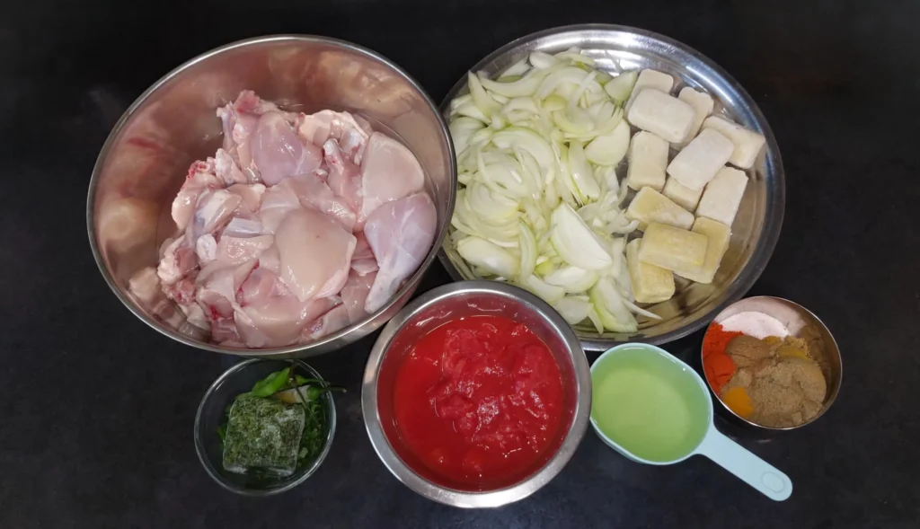 All ingredients required for chicken salan (skinless bone-in chicken, yellow onions, garlic, ginger, fresh coriander, fenugreek, small green chilli peppers, tinned tomatoes, sunflower oil, and spices)