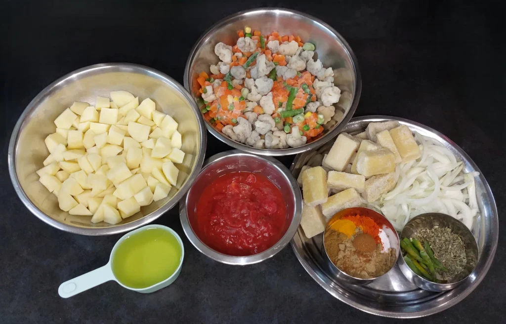 All ingredients required for mixed sabzi (potatoes, mixed vegetables, sunflower oil, tinned tomatoes, frozen crushed garlic cubes, frozen crushed ginger cubes, yellow onion, spices)
