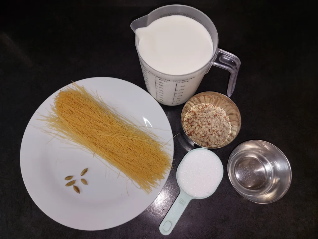 All ingredients required for seviyan (cardamom pods, vermicelli, milk, blended almonds, white granulated sugar, rosewater, and kewra water)