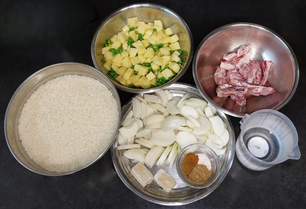 All ingredients for chicken pulao (Basmati rice, potatoes, peas, chicken, onions, ginger, spices, water)